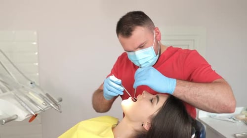 Dentist Examining Woman's Teeth in Clinic