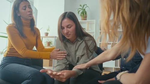 Friends Comforting Tearful Young Woman in Support Group