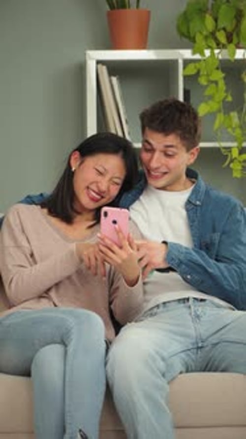 Cheerful Couple Smiling Together at Phone Indoors