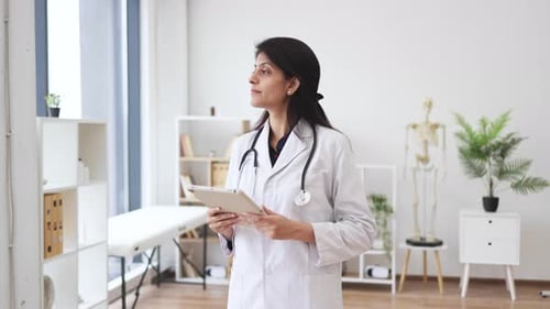 Therapist holding tablet while posing in doctor's office
