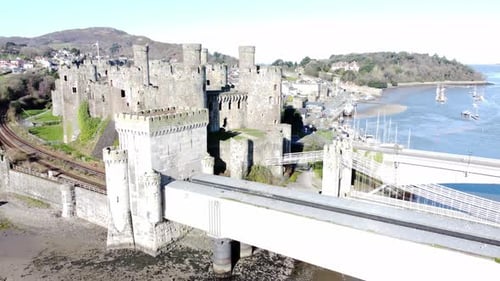 Medieval Conwy castle Welsh market town ruins aerial view historical harbour bridge dolly left shot