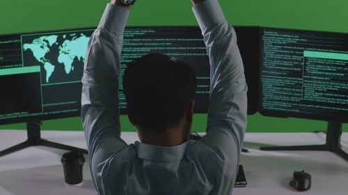 Müder asiatischer Mann, Entwickler, dehnt sich beim Schreiben von Code mit mehreren Computerbildschirmen auf grünem Bildschirm