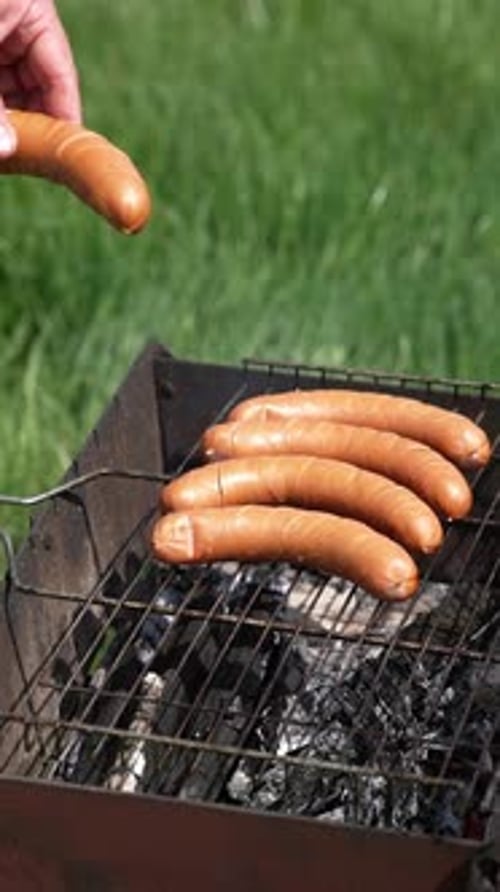Sausages roasting on barbecue grill outdoors. Grilled food fried and smoked in charcoal grills.