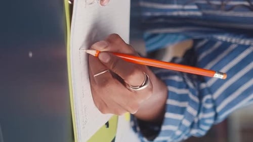 Hand Writes Notes with Orange Pencil