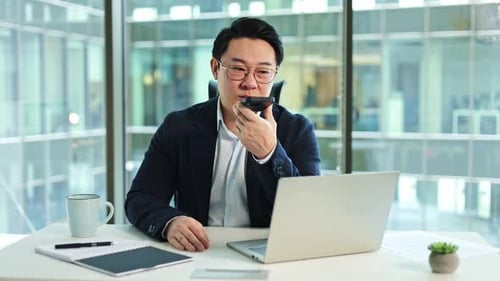 Korean Businessman Using Smartphone and Laptop in Modern Office