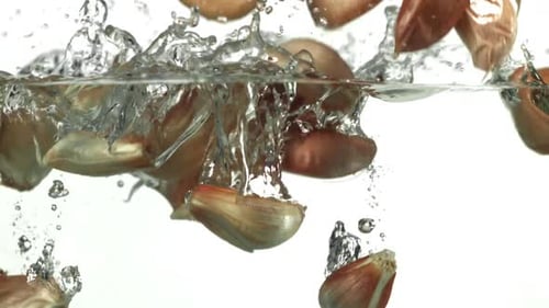 Los dientes de ajo caen bajo el agua filmados con una cámara de alta velocidad a 1000 fps