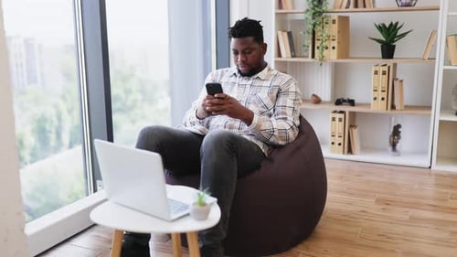 Man Relaxing in Beanbag Chair Using Smartphone