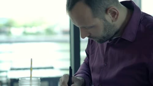Man Working With Documents And Drinking Juice In Cafe