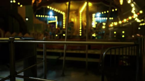An Empty Carousel Stands Illuminated in an Amusement Park at Night