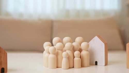 Wooden houses and plants encircle a crowd of wooden figures.
