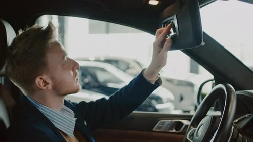 Man in Car Showroom Adjusts Sun Visor