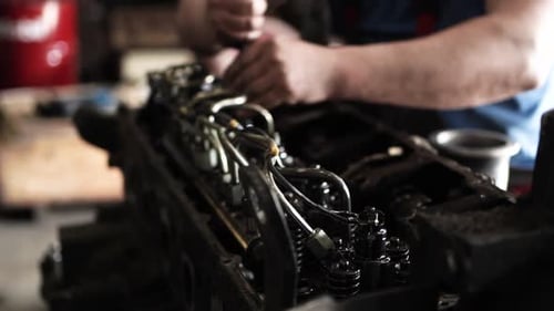 Mechanic Repairing Car Motor Engine with Screwdriver