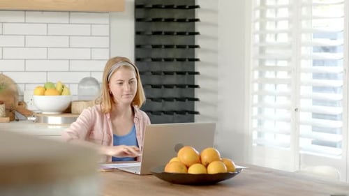 Young Woman Working on Laptop in Bright Kitchen