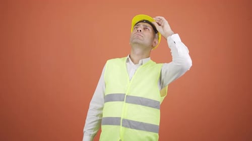 Looking up, the engineer is holding his hard hat.