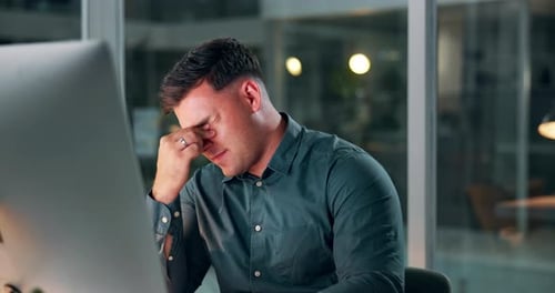 Office, tired and man with headache in night, working and typing on keyboard for project