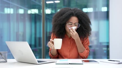 Woman with Cold Working at Office Desk