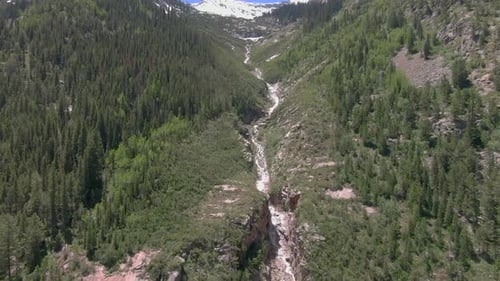 The aerial view pans down a beautiful 1,200-foot waterfall in Marble Colorado