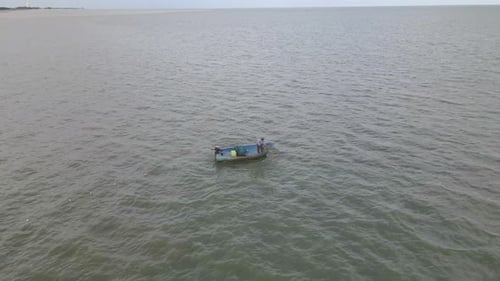 4K-Luftdrohnenaufnahmen eines Fischers in einem Holzboot, der in Thailand von oben ein Netz einzieht.