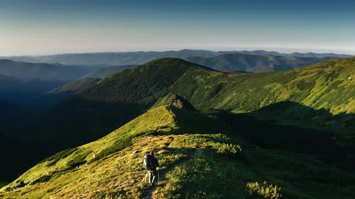 Hiker Walks Mountain Ridge Path During the Day