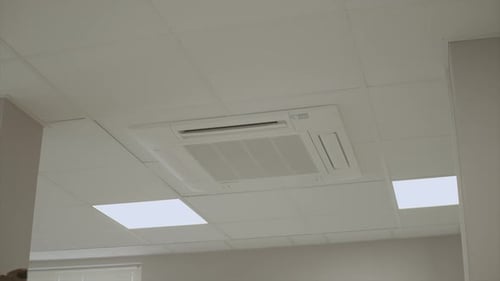 Arc Shot Of Central Air Conditioner Fixed In Ceiling of Business Office