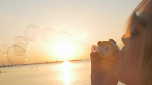 Frau bläst bei Sonnenuntergang Blasen am Strand