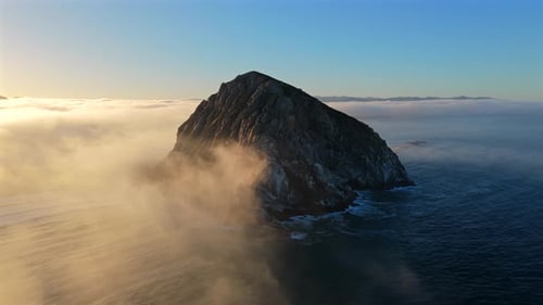 Breathtaking Serene Coastal Sunrise Over a Majestic Rock Island Surrounded By Soft Mist