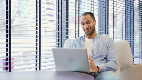 Young Man Video Conferencing on Laptop Indoors