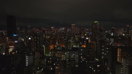 Aerial View of Tall Residential Buildings in Night City Forwards Fly Above Urban Borough Osaka Japan