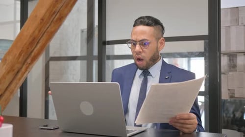 Adult Man Reacts Negatively to Paperwork at Desk