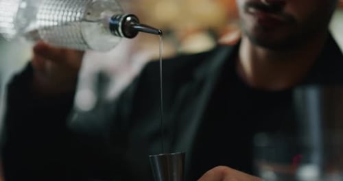 Close up of a professional bartender is preparing an alcoholic cocktail with ice cubes to customer