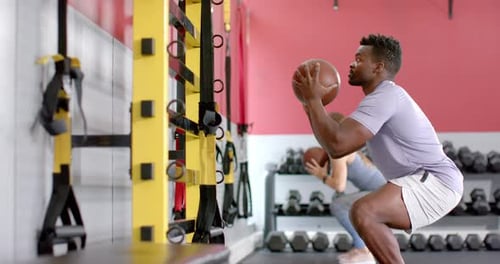 Fitte Afroamerikanerin und junge kaukasische Frau trainieren im Fitnessstudio mit Medizinball