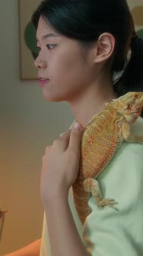 Femme asiatique avec un dragon barbu exotique sur l'épaule assise au bureau