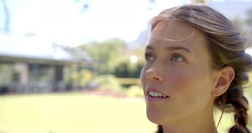 Smiling woman looking up, enjoying sunny day outdoors in garden, copy space