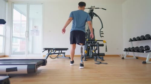 Asian young man with a prosthetic leg lift weight machines at the gym.