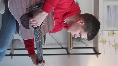 Young Adult Playing Acoustic Guitar at Home