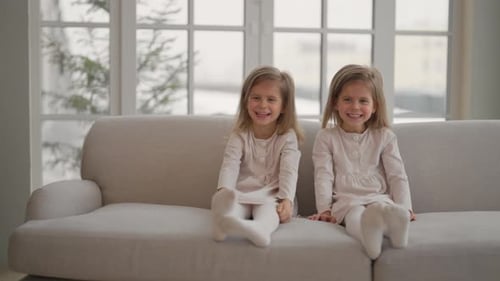 Two Charming Girls Laughing Together on Couch