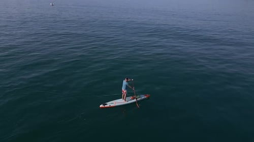 Aerial View of a Man Paddling a Standup Paddleboard or SUP Board on a Calm Sea