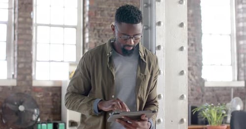 Handsome Man Works on Tablet in Bright Office