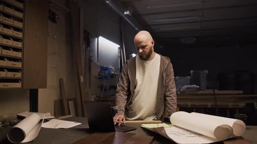 Portrait of Woodworker Using Laptop and Posing for Camera in Workshop