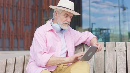 Mature Man Immersing in Tablet While Relaxing on Bench