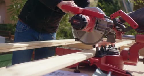 Adult Cutting Wood with Power Miter Saw