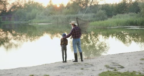 Grandfather and Child Fishing Together at Lakeside Sunset