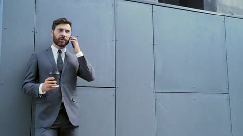 Caucasian bearded employee on urban background office building texting Messages, read good new