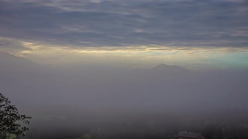 Fog drifts in over farmland in a valley in the Austrian alps - time lapse