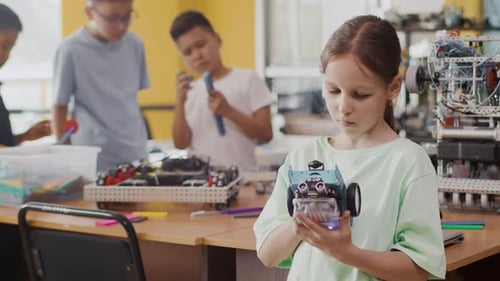 Girl Examines Robot in Classroom with Other Students