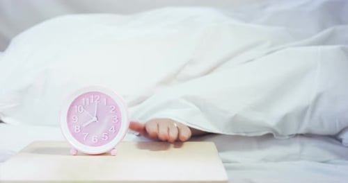Hand Turns Off Alarm Clock in Bed