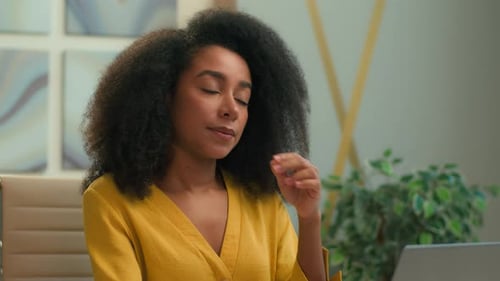 Woman Massaging Face at Desk in Office