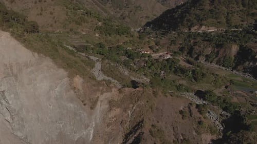 village in a remote mountain region valley surrounded by trees river rock slide approaching aerial r