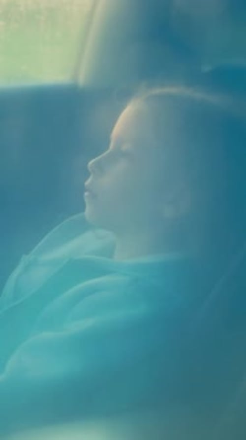 Pensive Child Waits for Parents in Car on Rainy Day