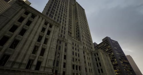 Edificio alto bajo un cielo nublado con las luces de la ciudad brillando al anochecer